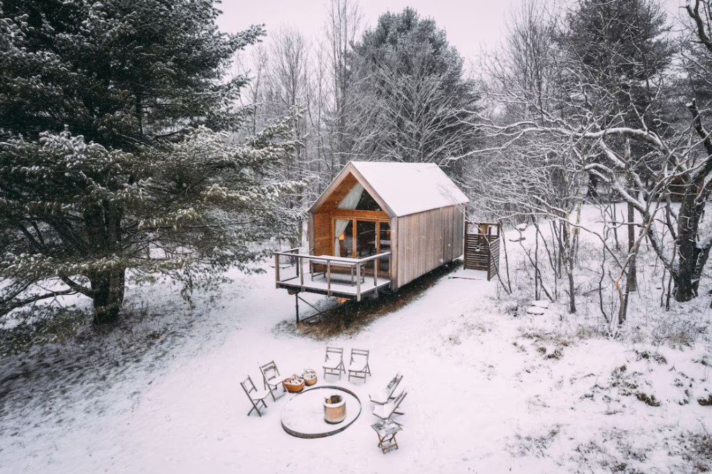 A cabin deck with a fire pit in the snow