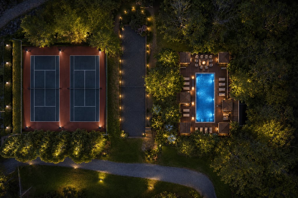 Tennis courts and pool lit up at night, seen from above