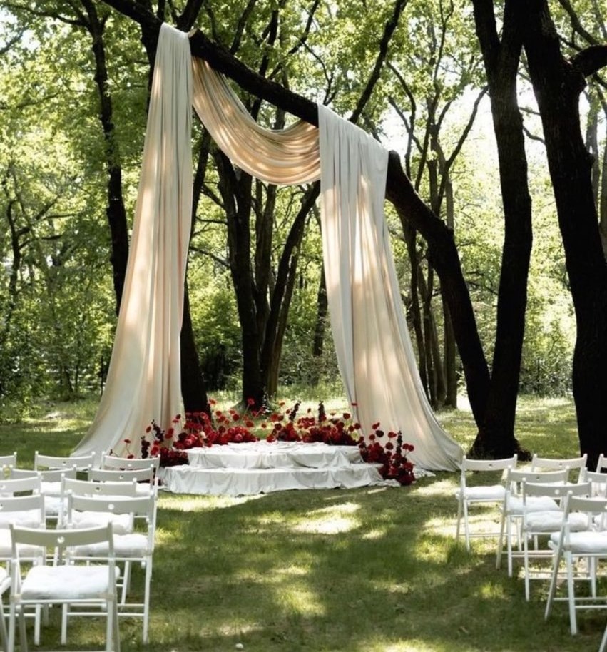 A ceremony arch of white linen in the woods